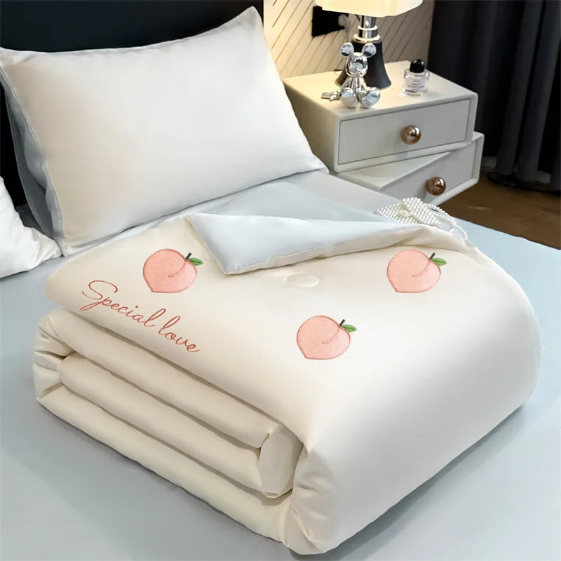 A white embroidered cooling summer quilt folded neatly on a light blue surface.