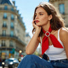 A woman with long brown hair wearing a white tank top and blue jeans, looking to the side.