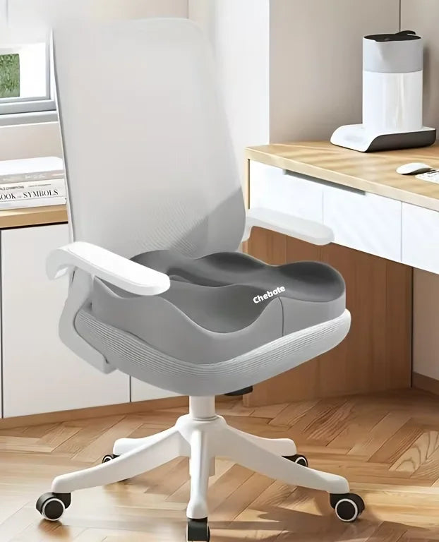 A gray ergonomic memory foam seat cushion mounted on a white office chair with wheels.