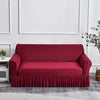 A deep red dustproof stretch sofa slipcover displayed against a white wall.