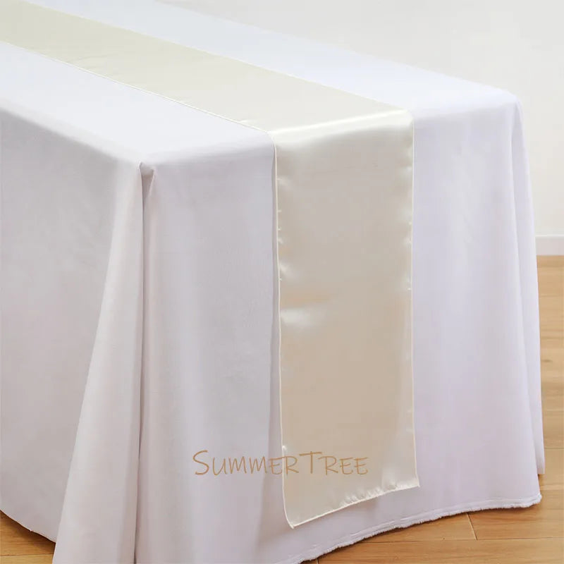 Elegant satin table runner draped across a white tablecloth.