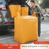 A woman is loading a large yellow waterproof storage sack into the trunk of a car for moving and packing.