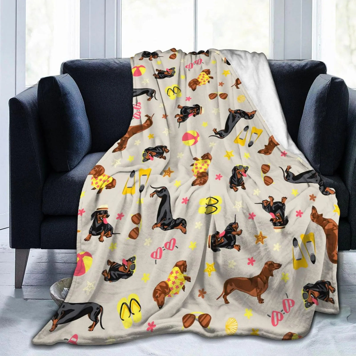 A tan and yellow patterned flannel blanket draped over a dark gray sofa.