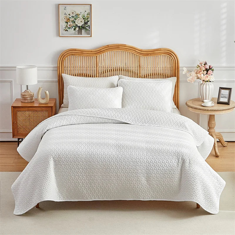 A white quilted bed with a wooden headboard and bedding set in a bright bedroom.