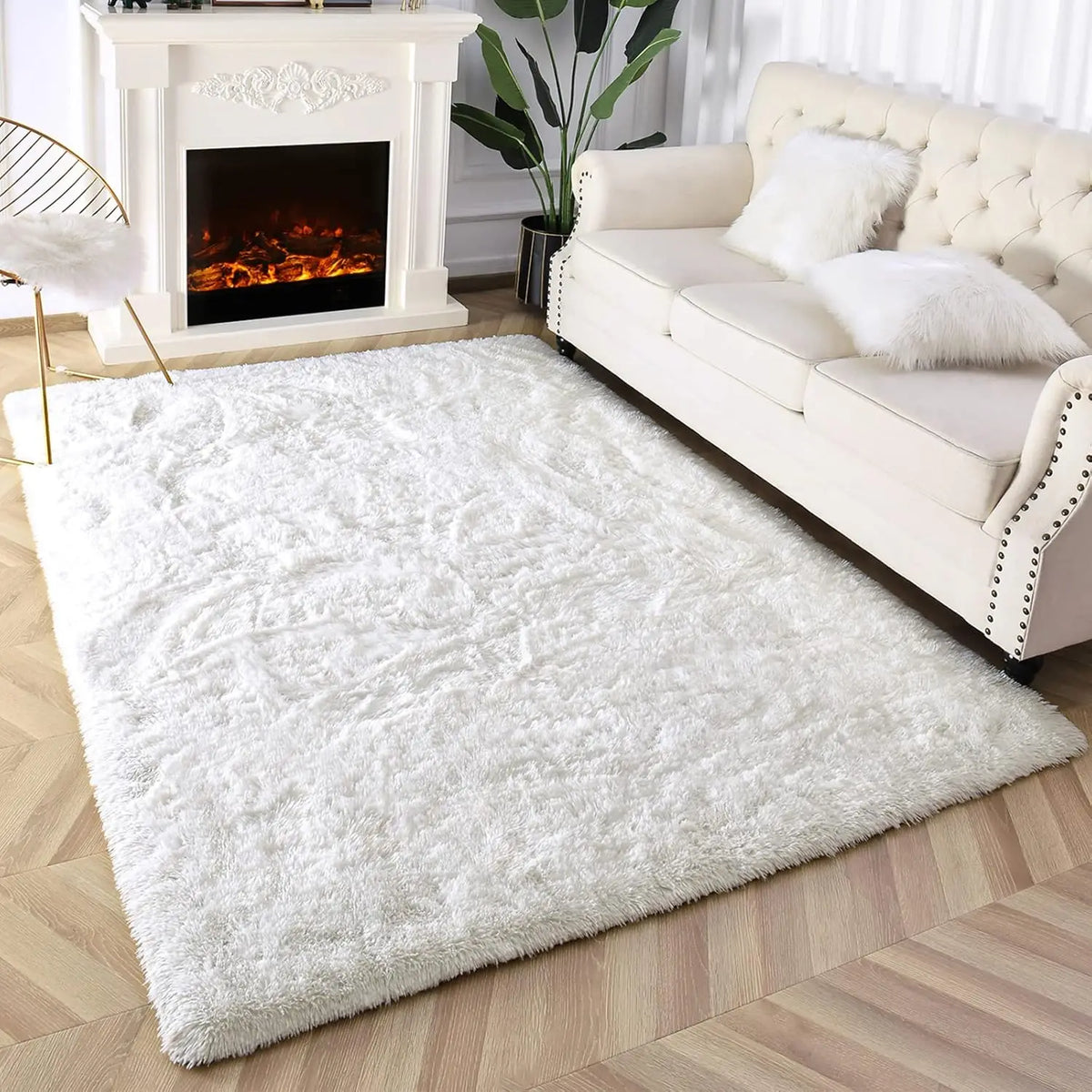 A fluffy white tie-dyed plush floor mat placed in front of a cream upholstered sofa and a white fireplace.