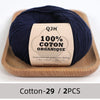 A ball of dark navy organic cotton yarn labeled QJH 100% COTON ORGANIQUE placed in a wooden tray.