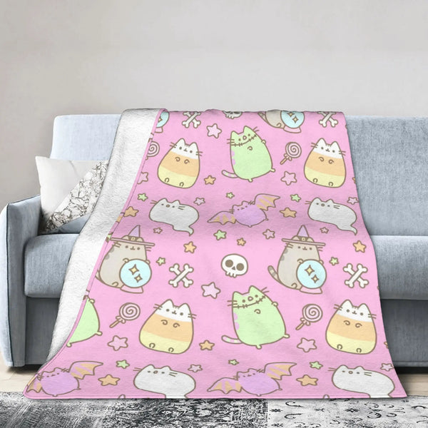 A pink patterned coral fleece cat plush throw blanket draped over a gray sofa.