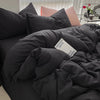 A dark gray duvet cover set with pillows and a pink pillow visible on a bed.
