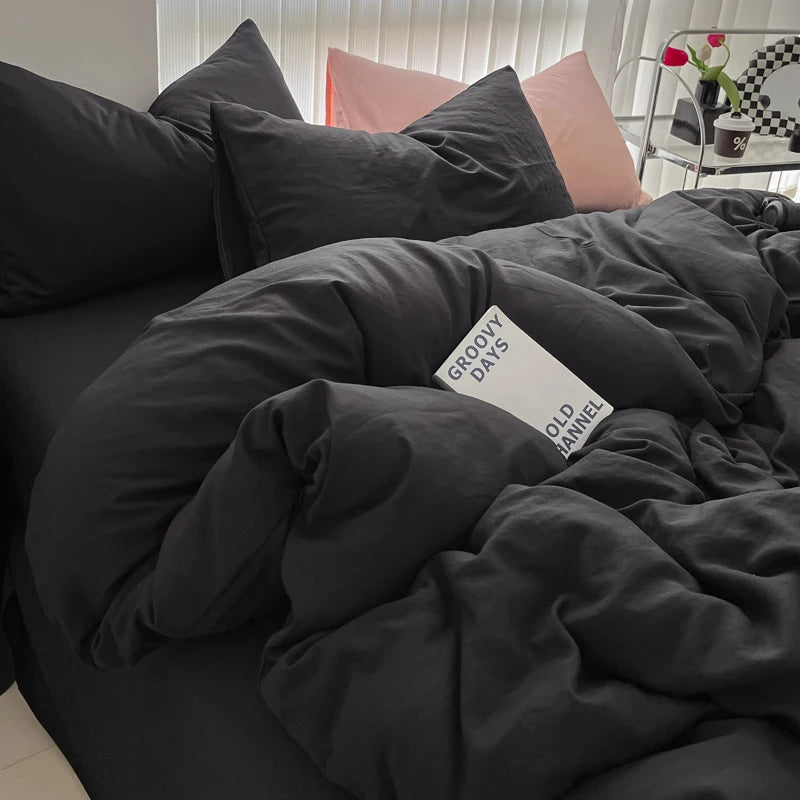 A dark gray duvet cover set with pillows and a pink pillow visible on a bed.