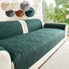 A dark green quilted sofa cushion with a white trim and decorative fabric swatches displayed above.