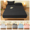 A set of brushed elastic fitted bed sheets in various colors including gray, beige, blue, and pink displayed on a wooden bed 