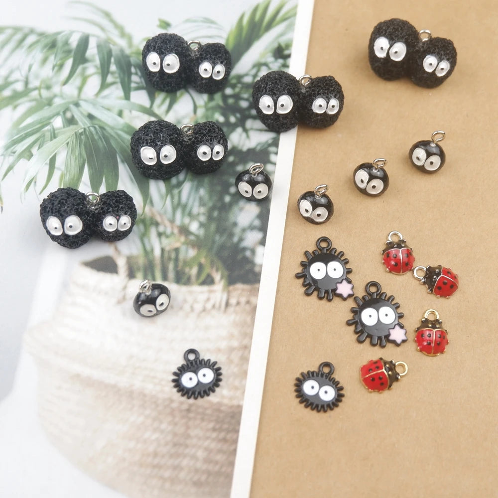 A collection of black and silver ladybug resin charms displayed on a brown card next to green foliage.
