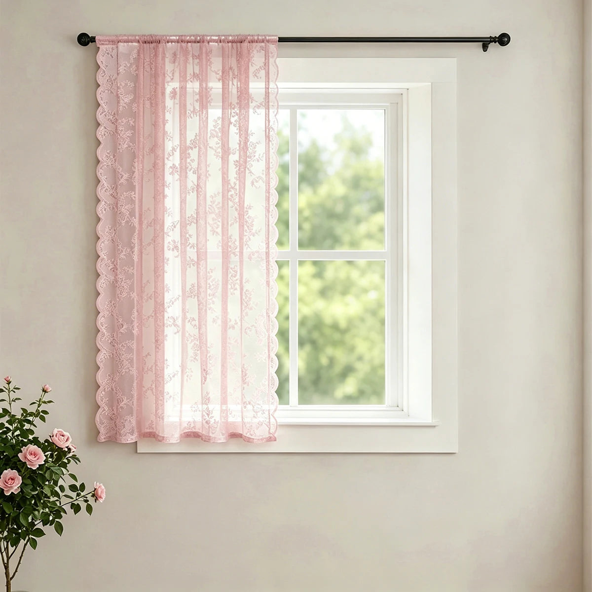 Pink vintage French-style lace curtain with a wave border hanging in a white window frame.
