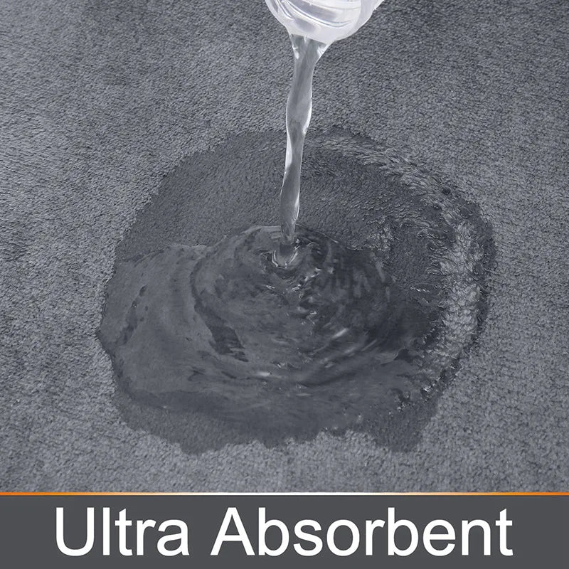 A close-up shot of a clear liquid dripping onto a dark gray ultra absorbent memory foam bathroom mat.