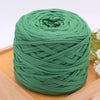 A ball of green craft yarn for knitting and DIY resting on a wooden surface.