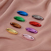 Eight plastic safety pins in various bright colors including blue, green, silver, red, and purple displayed on pink fabric.