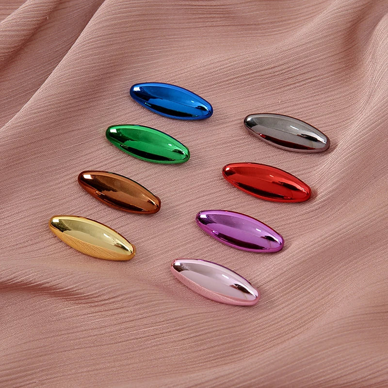 Eight plastic safety pins in various bright colors including blue, green, silver, red, and purple displayed on pink fabric.