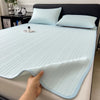 A hand is touching a light blue cooling ice silk bed pad with vertical ribbing on a bed.