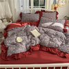 A princess style bedding set featuring a red and gray patterned duvet, pillows, and ruffled bed frame.