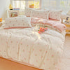 A light pink floral printed bedding set with matching pillows and a duvet on a bed.