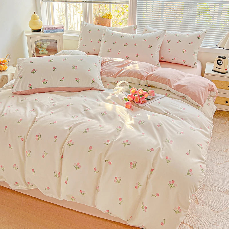 A light pink floral printed bedding set with matching pillows and a duvet on a bed.
