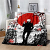 A red and black patterned throw blanket featuring a silhouette of a character in a dark outfit against a background of trees 