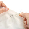 A hand is using a stainless steel T-pin to mark fabric for knitting blocking or sewing.