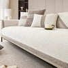 A light beige linen sofa cover with neutral throw pillows and a green mug resting on the fabric.