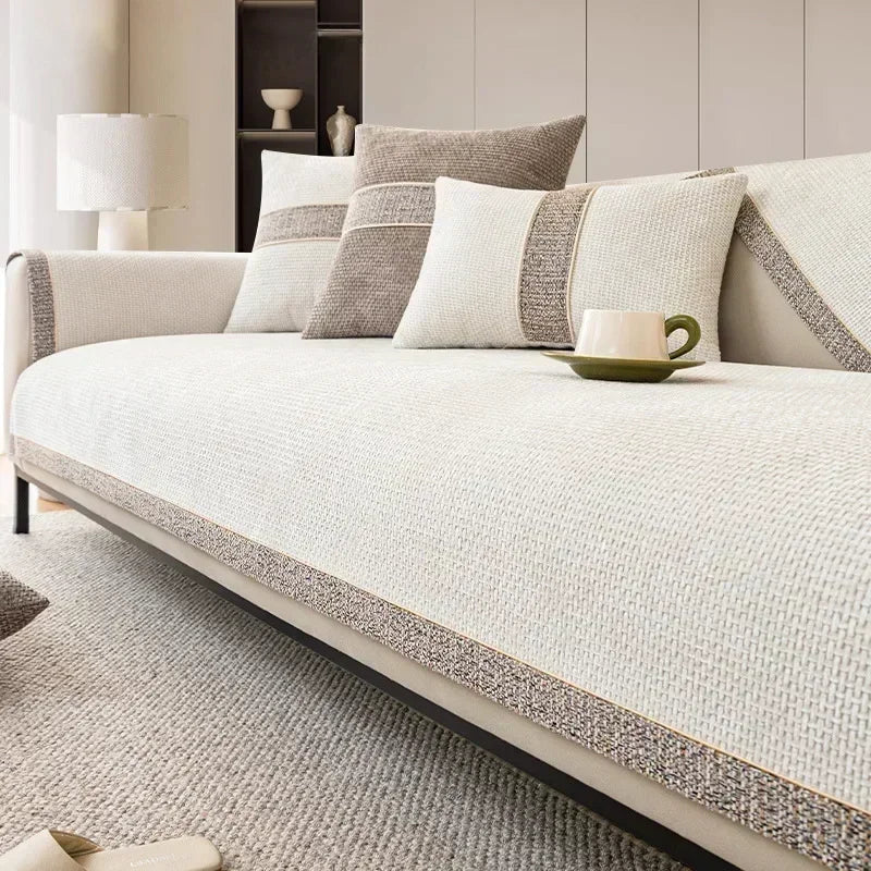 A light beige linen sofa cover with neutral throw pillows and a green mug resting on the fabric.