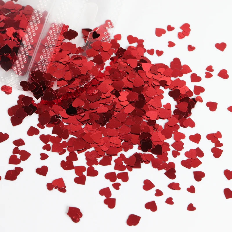 A pile of red heart-shaped glitter filler for epoxy art scattered on a white surface.