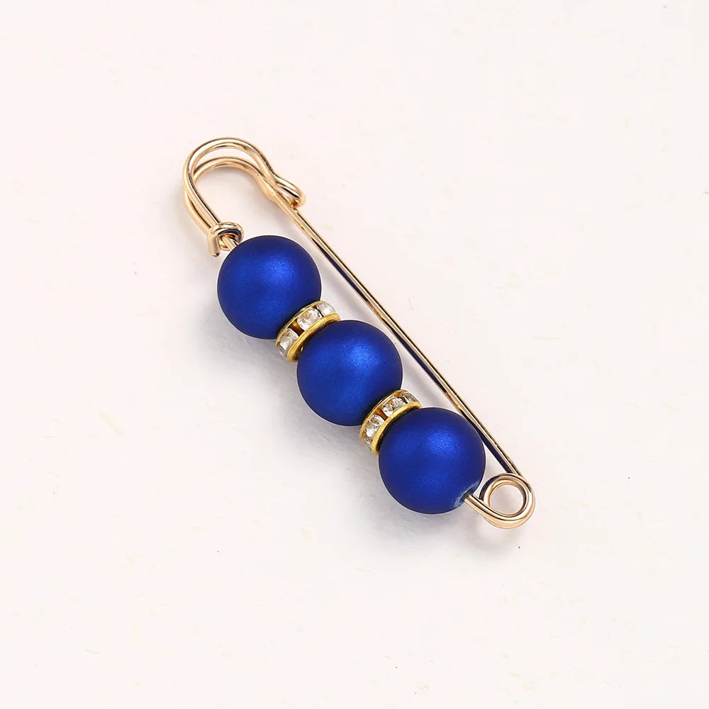 A gold-toned adjustable pearl brooch featuring three round blue beads and a diamond accent.