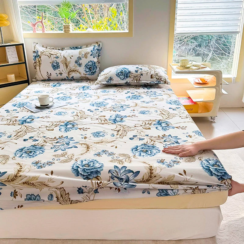 A floral print fitted bed sheet featuring blue and beige flowers displayed on a bed.