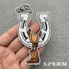 An embroidered patch shaped like the letter U featuring a cowboy figure on a rustic background.