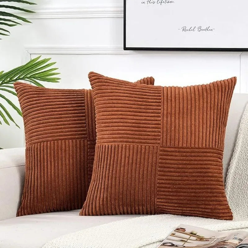 A patchwork pillow cover made of brown corduroy fabric with vertical stripes on a white sofa.