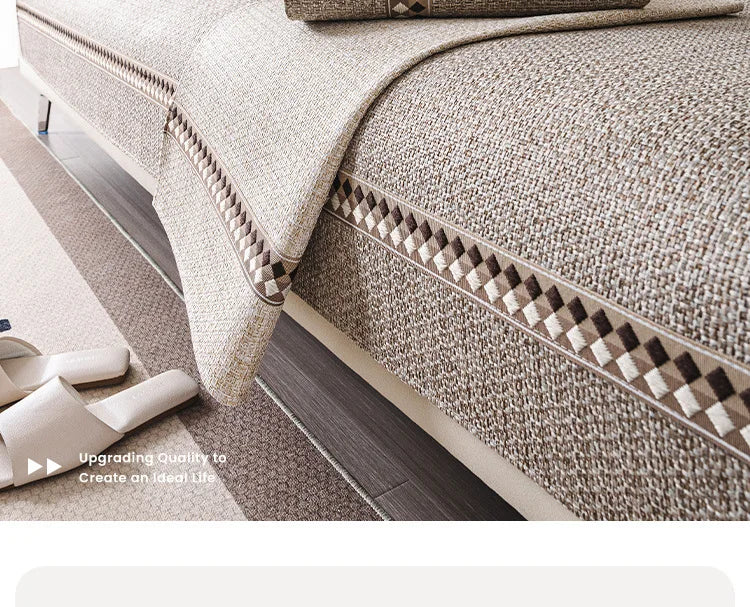 A close-up of a beige linen sofa cover featuring a textured fabric and decorative piping.
