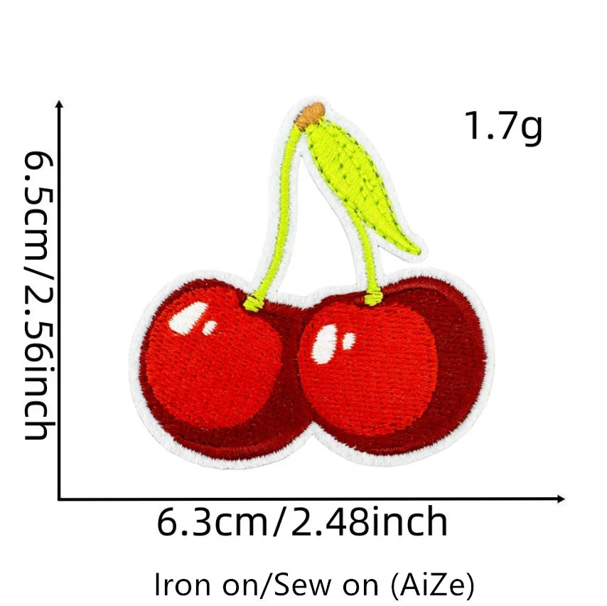 A yellow cherry embroidered patch on a green fabric background, measuring 1.7g.
