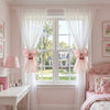 A pair of sheer pink ribbon bow curtain tiebacks framing a window in a light pink room.