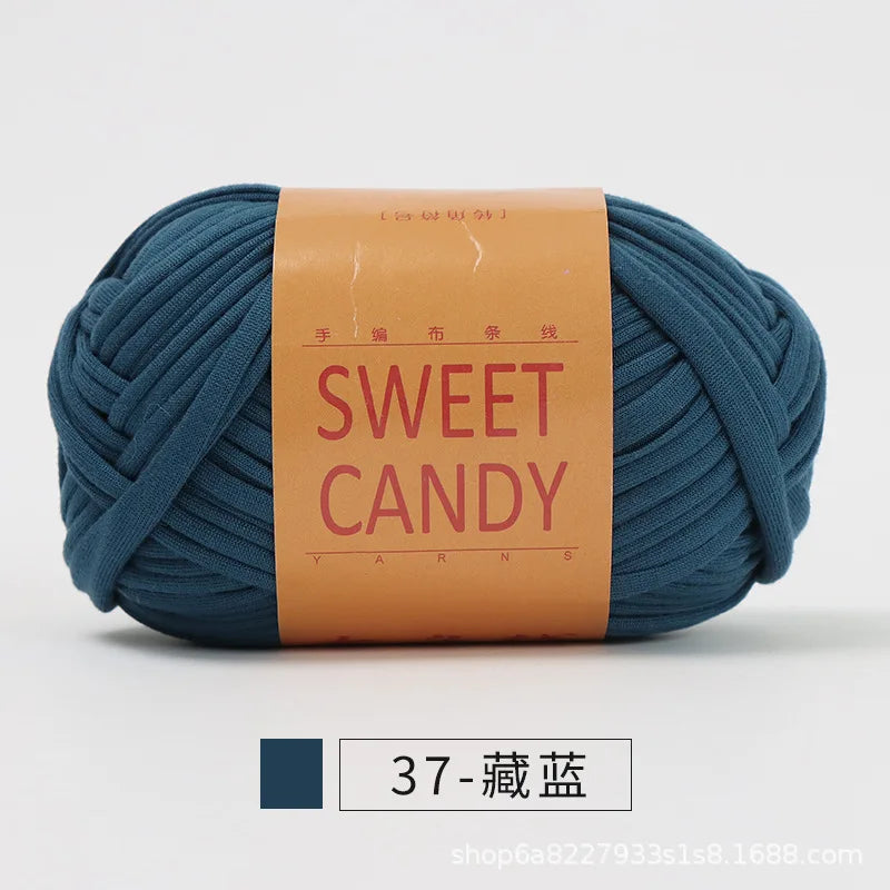 A skein of dark teal hand-dyed fabric strip yarn labeled SWEET CANDY with Chinese characters.