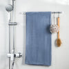 A blue towel hanging on a chrome shower rod with wooden hooks for curtain rods.