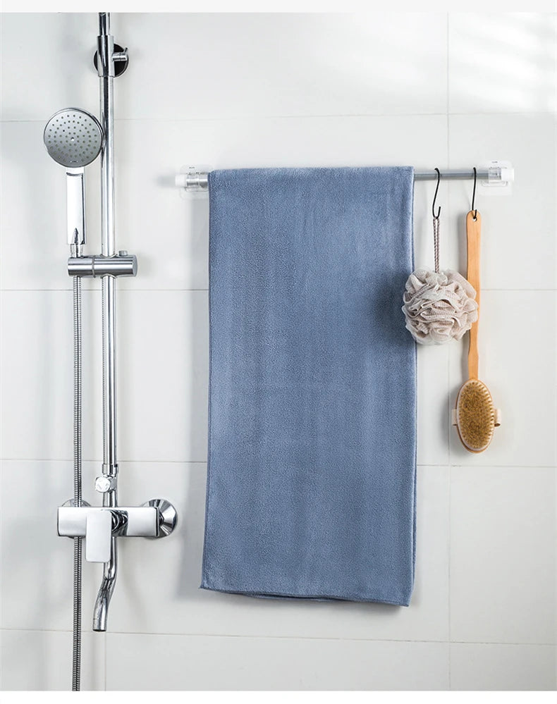A blue towel hanging on a chrome shower rod with wooden hooks for curtain rods.