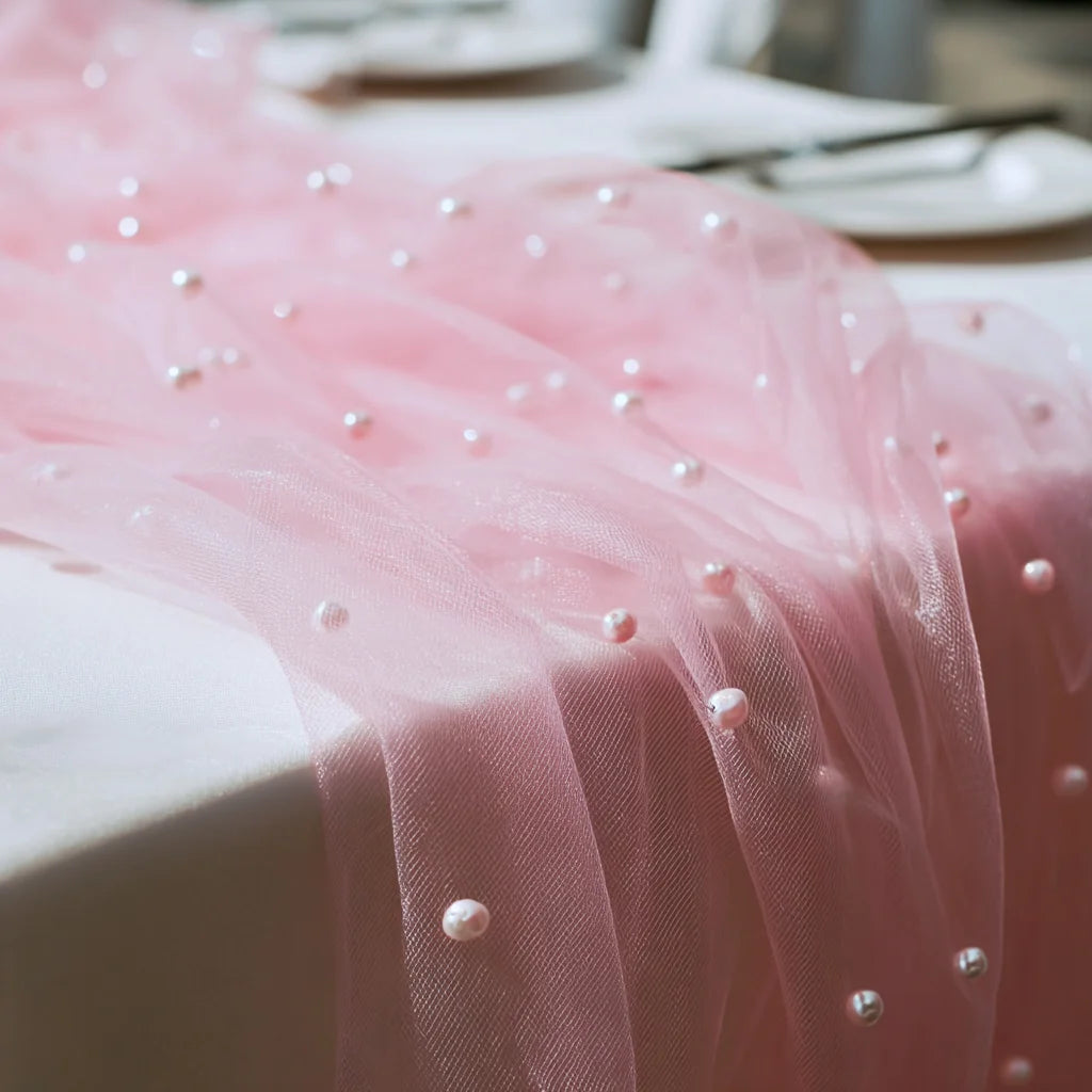 Pink pearl tulle table runner draped elegantly on a white surface.