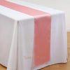 Elegant satin table runner in peach color draped across a white tablecloth.