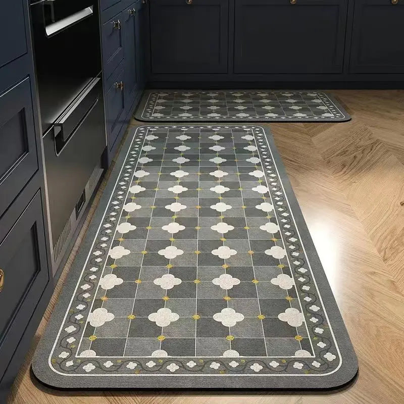 A rectangular gray and beige anti-slip floor mat placed on a light wood floor next to dark cabinetry.