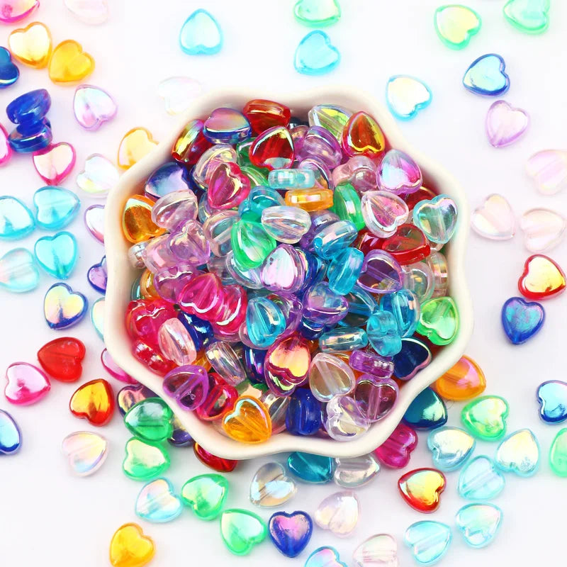 A pile of colorful acrylic heart beads in various shades of pink, blue, green, and yellow for jewelry making.