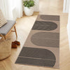 A long runner rug with black concentric geometric lines on a beige background placed on a light wood floor.
