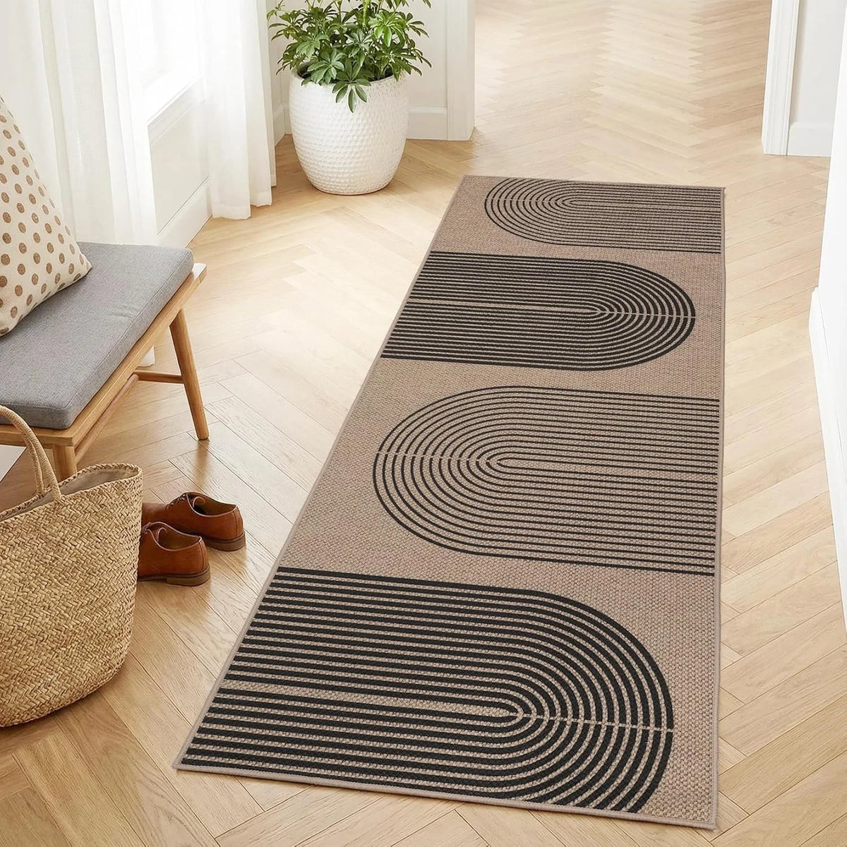 A long runner rug with black concentric geometric lines on a beige background placed on a light wood floor.