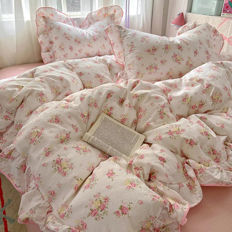 A floral bedding set featuring white fabric with pink and green floral patterns, including pillows and a duvet.
