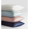 A stack of four mulberry silk satin pillowcases in white, light blue, pink, and navy.