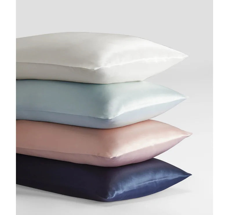 A stack of four mulberry silk satin pillowcases in white, light blue, pink, and navy.