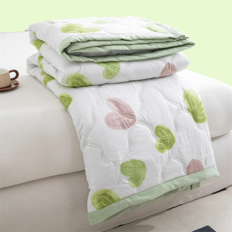 White duvet cover with light green and pink floral patterns folded on a white surface.
